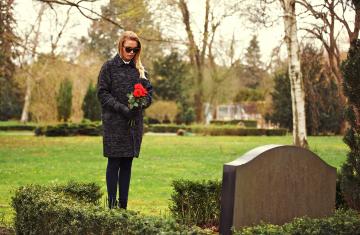 Woman visiting a cemetery with flowers. 